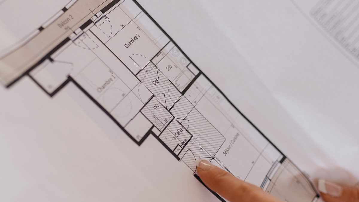 Alexandra Durand pointe une pièce sur le plan de vente d'un appartement neuf.
